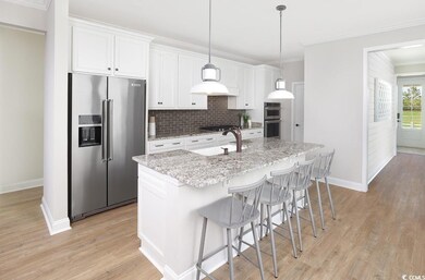 Kitchen with stainless steel appliances, an island with sink, tasteful backsplash, white cabinets, and crown molding