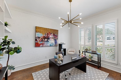 Office area with crown molding, a chandelier, and dark wood-type flooring