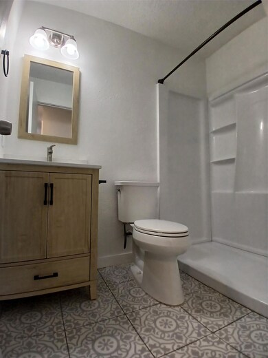 Bathroom featuring a shower, toilet, tile pattern