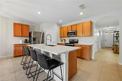 Kitchen with a breakfast bar area, light countertops, light tile patterned floors, appliances with stainless steel finishes, and arched walkways