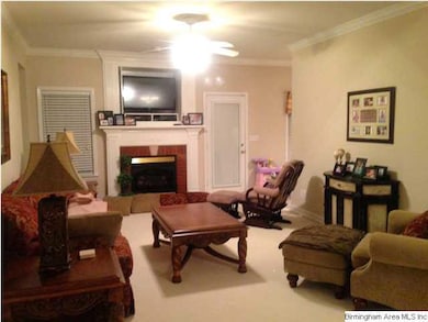 Living room with gas log fireplace. The kitchen is