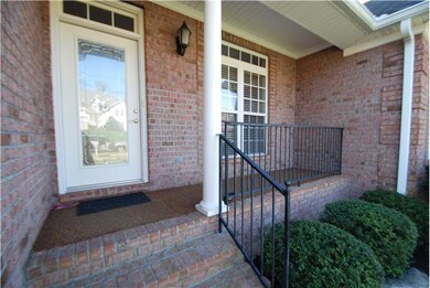 Covered front porch is big enough for chairs or bench, and leaded glass front door is welcoming.