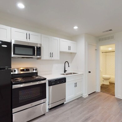 Kitchen featuring stainless steel appliances, white cabinets, light wood-type flooring, and recessed lighting