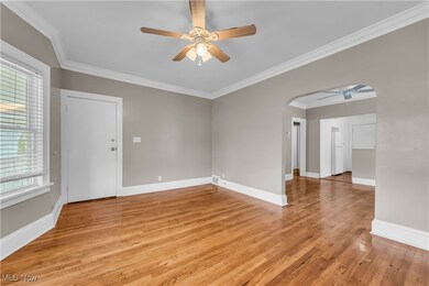 Empty room featuring light wood-type flooring, ceiling fan, and ornamental molding