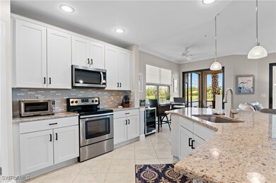 Kitchen featuring appliances with stainless steel finishes, white cabinetry, decorative backsplash, pendant lighting, and light tile patterned floors