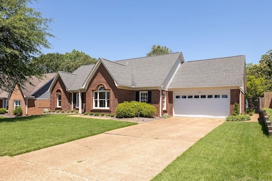 View of front of home with brick siding, a garage, roof with shingles, and concrete driveway