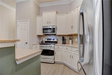 Kitchen featuring tasteful backsplash, white cabinets, ornamental molding, stainless steel GE gas stove and fridge, and light wood-type flooring