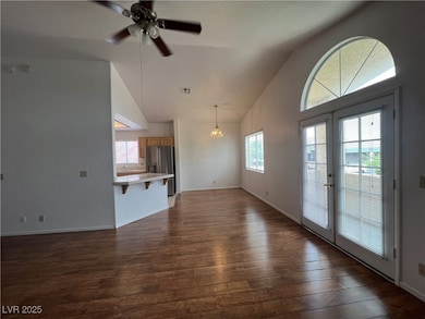 Unfurnished living room with french doors, a ceiling fan, dark wood-type flooring, high vaulted ceiling, and a chandelier