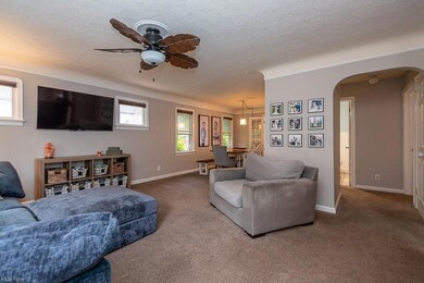 Living room featuring a textured ceiling, a wealth of natural light, dark carpet, and ceiling fan
