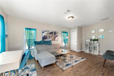 Living room with wood finished floors, visible ven