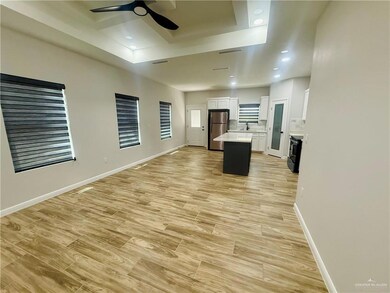Kitchen featuring open floor plan, a center island, freestanding refrigerator, light wood finished floors, and white cabinets