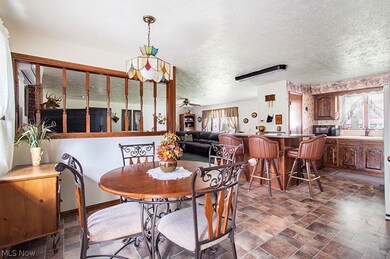Tiled dining space with a textured ceiling, ceiling fan, and sink