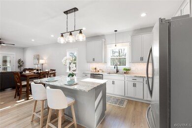 Kitchen featuring hanging light fixtures, a kitchen island, appliances with stainless steel finishes, light hardwood / wood-style flooring, and white cabinetry