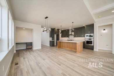 Kitchen featuring stainless steel appliances, tasteful backsplash, light countertops, light wood finished floors, and an island with sink