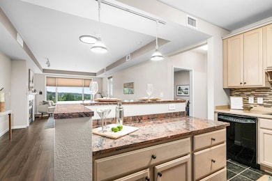 Kitchen featuring dishwasher, backsplash, open floor plan, a tray ceiling, and cream cabinets