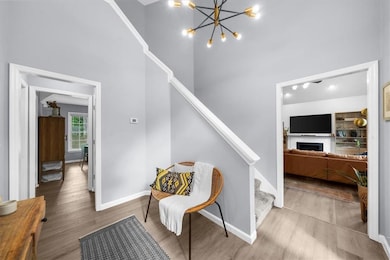 Stairs featuring a towering ceiling, wood finished floors, baseboards, a fireplace, and a chandelier