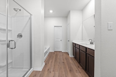 Full bathroom featuring dark wood-type flooring, vanity, a garden tub, and a shower stall