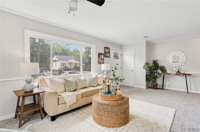Living room with light carpet, a textured ceiling, ornamental molding, and ceiling fan