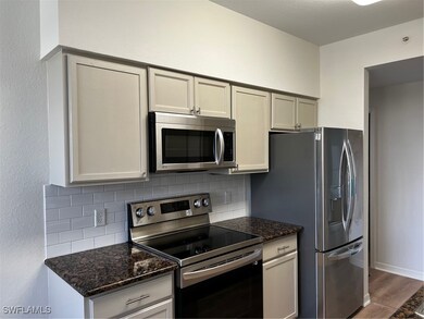 Kitchen featuring stainless steel microwave, stove, decorative backsplash, and wood finished floors