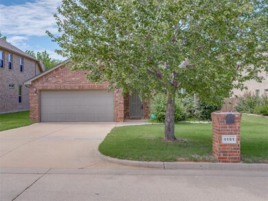 View of property hidden behind natural elements featuring a front yard and a garage
