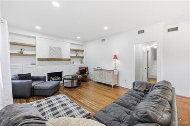 Living room featuring wood finished floors, ornamental molding, a fireplace, recessed lighting, and built in shelves