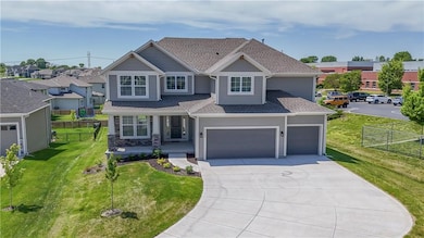 View of front of property with concrete driveway, roof with shingles, a porch, a garage, and stone siding