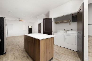 Clothes washing area with laundry area, visible vents, light wood-style floors, ceiling fan, and separate washer and dryer