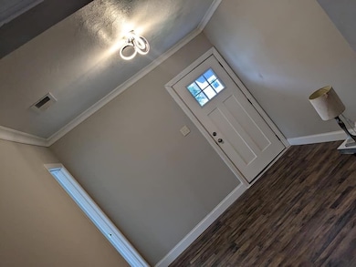Foyer entrance with a textured ceiling, crown molding, and dark hardwood / wood-style floors