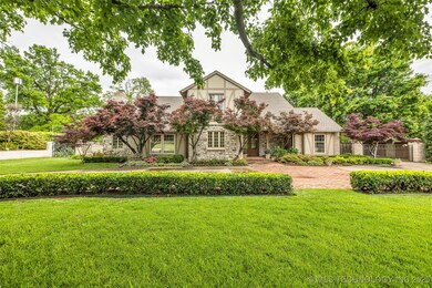 English style home with stone siding, a chimney, a