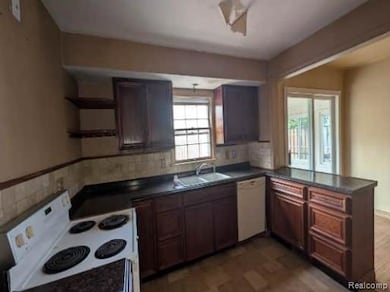 Kitchen with white appliances, dark countertops, open shelves, and a peninsula