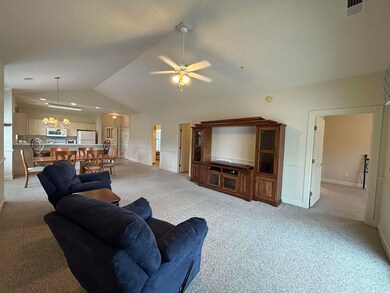 Carpeted living room with ceiling fan and vaulted 