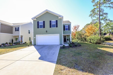 View of front of house with a front yard, concrete driveway, and a garage