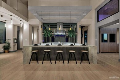 Kitchen featuring pendant lighting, a towering ceiling, light wood-type flooring, and island range hood