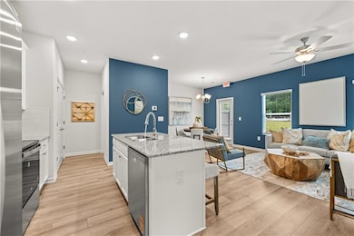 Kitchen featuring white cabinets, light stone counters, a kitchen breakfast bar, a chandelier, and appliances with stainless steel finishes