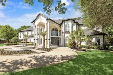 This photo showcases a grand two-story home with a striking entrance featuring tall white columns and large, arched windows. The landscaped front yard includes a circular driveway, a fountain, and lush greenery.