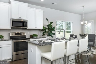 Kitchen featuring appliances with stainless steel finishes, tasteful backsplash, a breakfast bar area, a kitchen island with sink, and dark wood-style floors