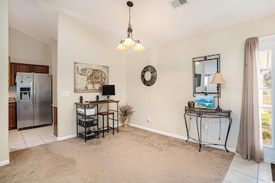 Dining space featuring light carpet, light tile patterned floors, lofted ceiling, and a chandelier