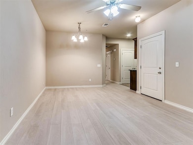 Unfurnished room featuring a chandelier, light wood-type flooring, and ceiling fan
