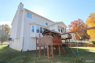 Rear view of property with a lawn, a playground, a chimney, and a wooden deck