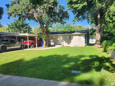Single story home featuring a front lawn, brick siding, a chimney, and a carport
