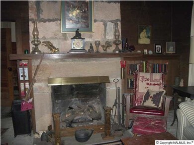 Fireplace in living room made of cut stone. Fitted with gas logs.