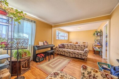 Living room featuring light wood-style floors, ornamental molding, and a textured ceiling
