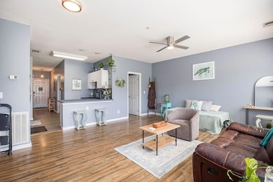 Living area featuring a ceiling fan, wood finished floors, and baseboards