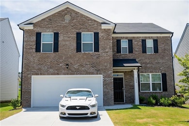 View of front of house with a garage, concrete driveway, brick siding, and a front lawn