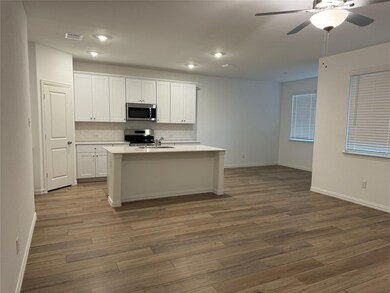 Kitchen featuring white cabinets, tasteful backsplash, stainless steel appliances, an island with sink, and hardwood / wood-style flooring