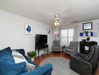 Living area with a textured ceiling, wood finished floors, and ceiling fan