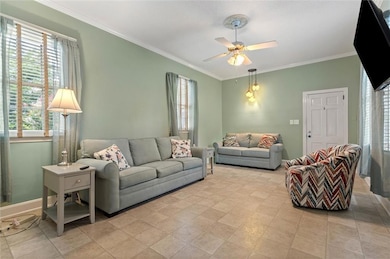 Living room featuring healthy amount of natural light, ceiling fan, and crown molding