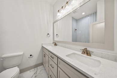 Bathroom with double vanity and light marble finish floors