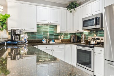 Kitchen with decorative backsplash, dark stone counters, white cabinets, and appliances with stainless steel finishes