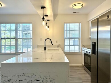 Kitchen featuring stainless steel appliances, a peninsula, a sink, visible vents, and light wood-style floors